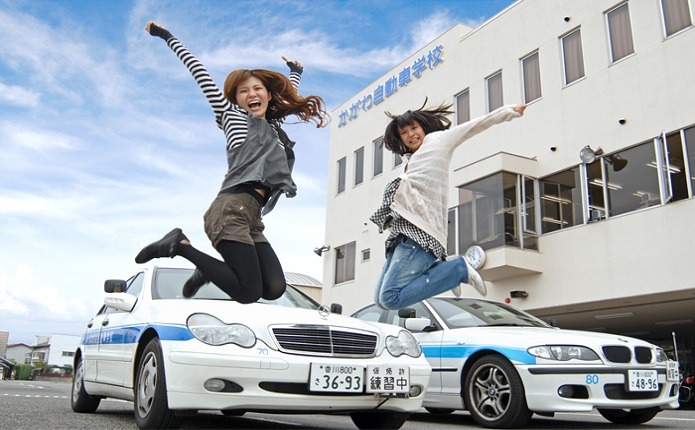 校舎と教習車をバックにジャンプ!